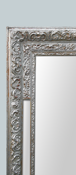 Cadre miroir argenté patiné à decor de rinceaux feuillages et fleurs.